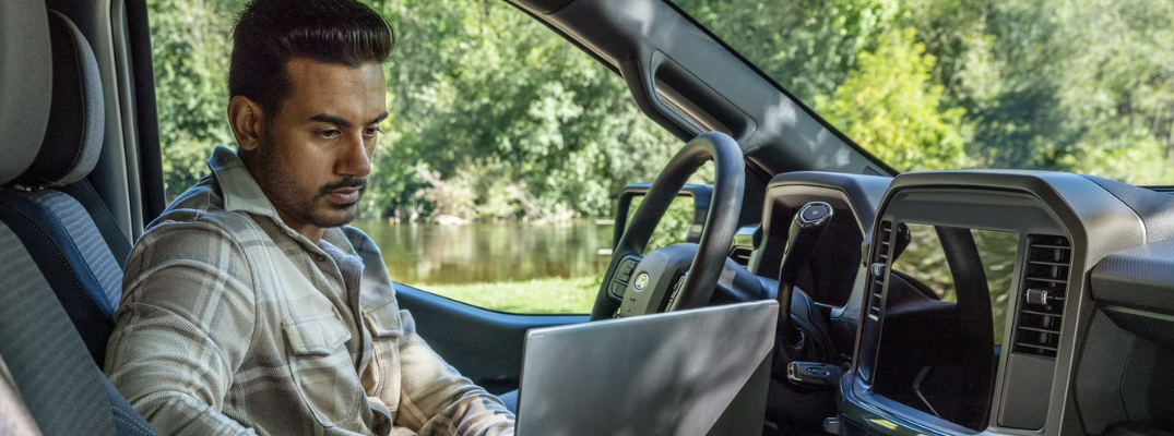 A man on his laptop in his Ford truck